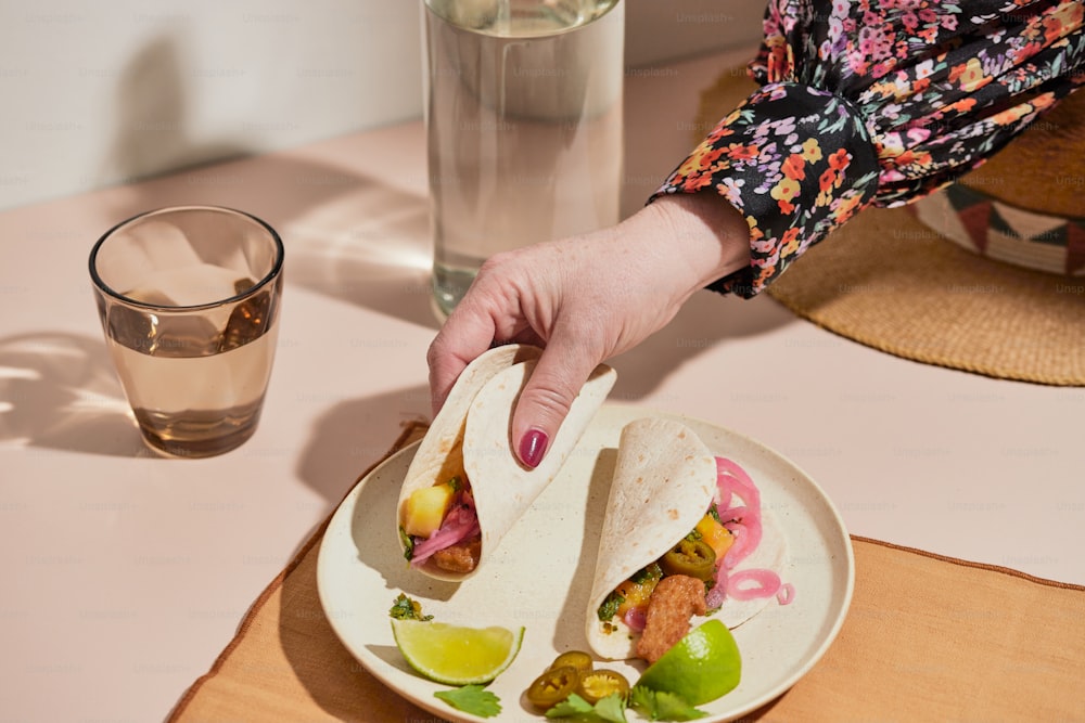 a person holding a tortilla on a plate