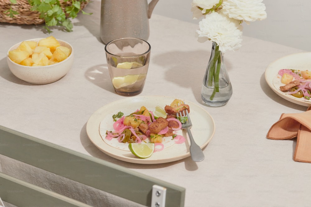 a table topped with plates of food and a vase of flowers