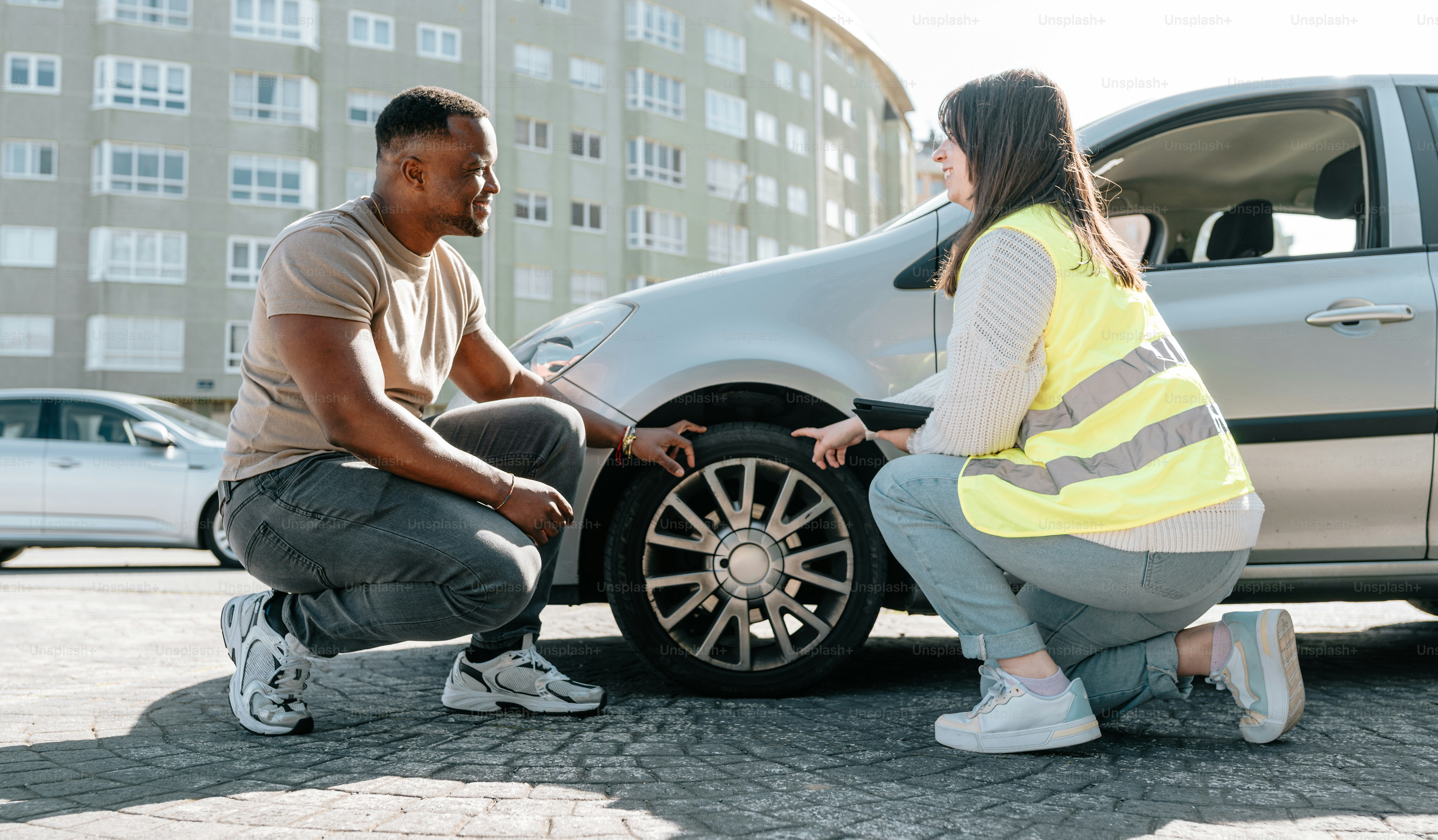 un homme et une femme regardant un pneu de voiture