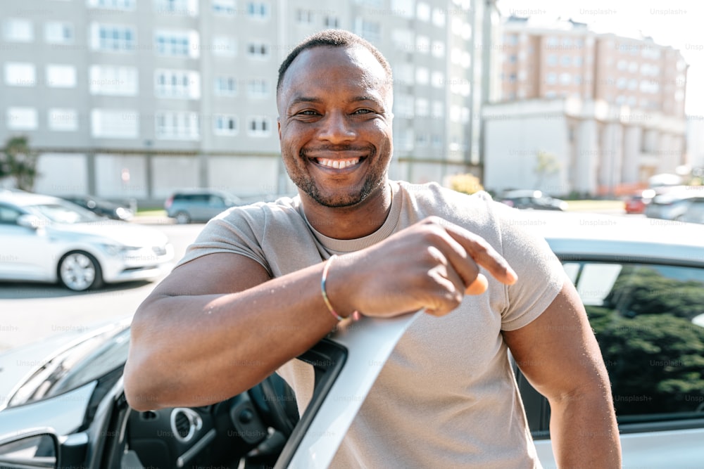 a man standing in front of a car smiling