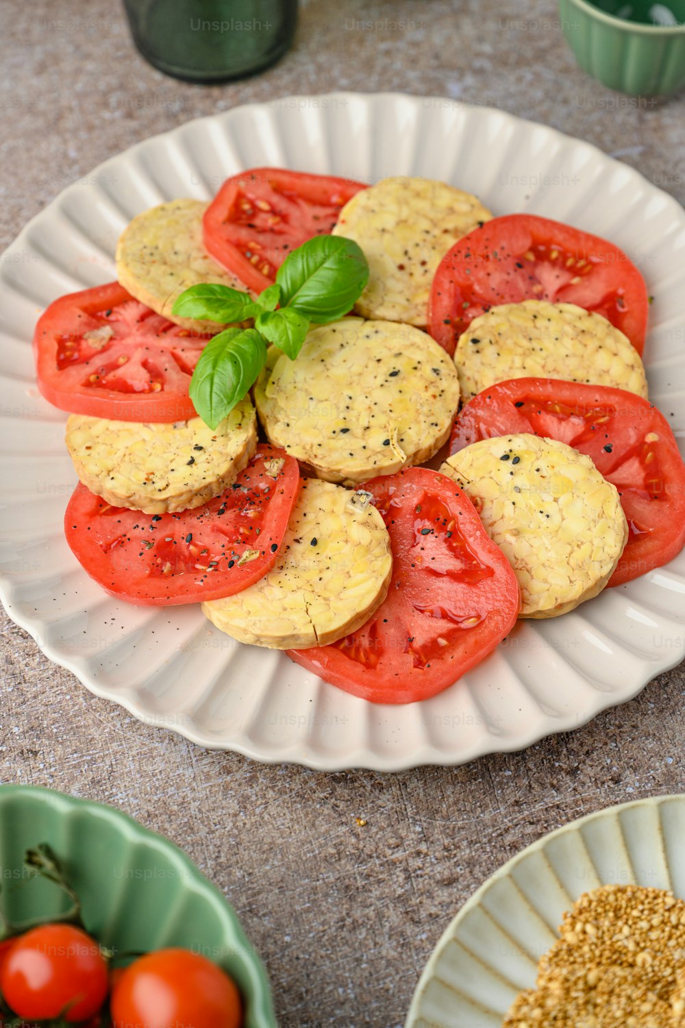 a white plate topped with sliced tomatoes and crackers
