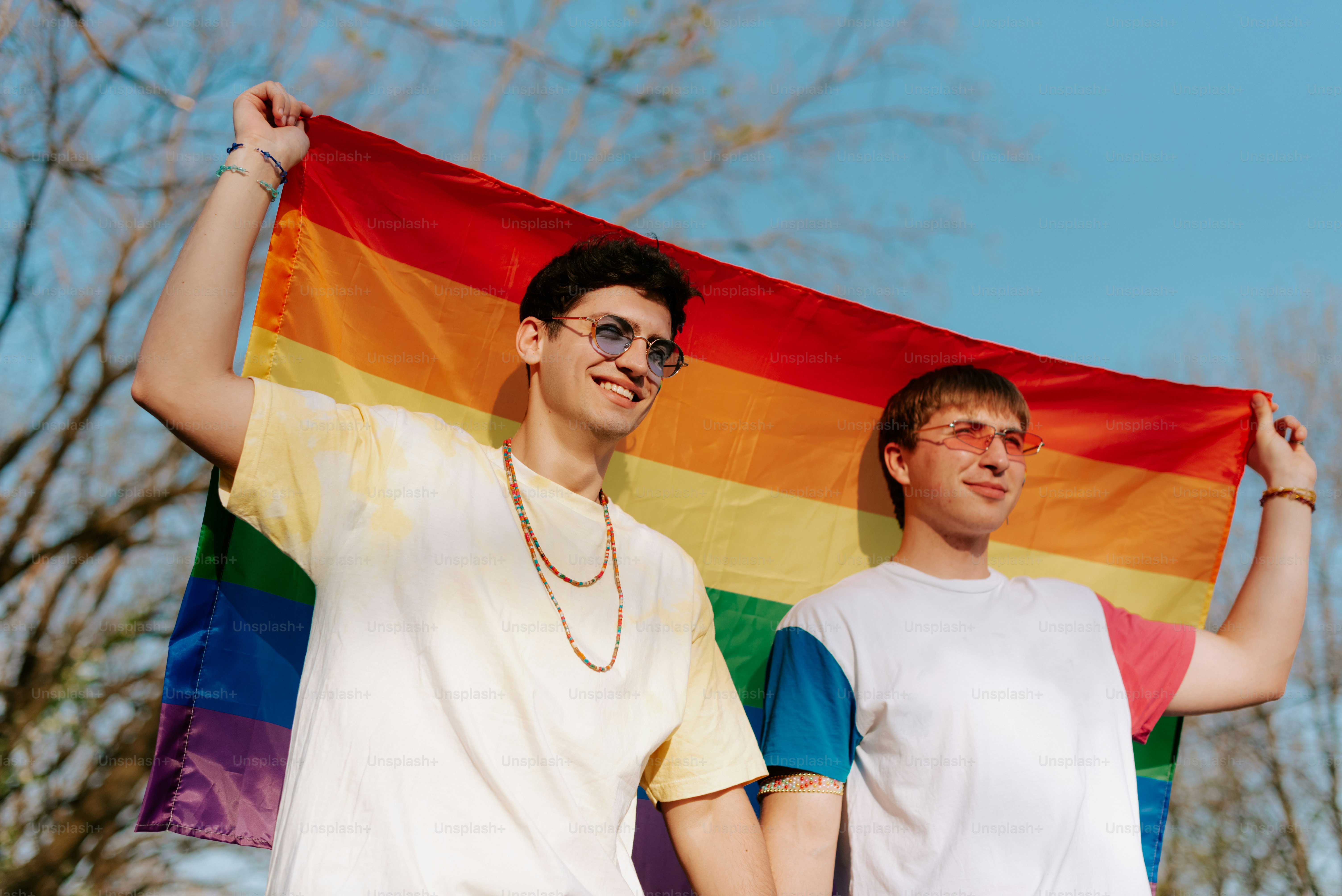 A couple of people holding hands in front of a rainbow flag photo ...