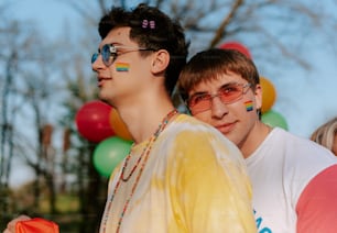 two young men standing next to each other in front of balloons
