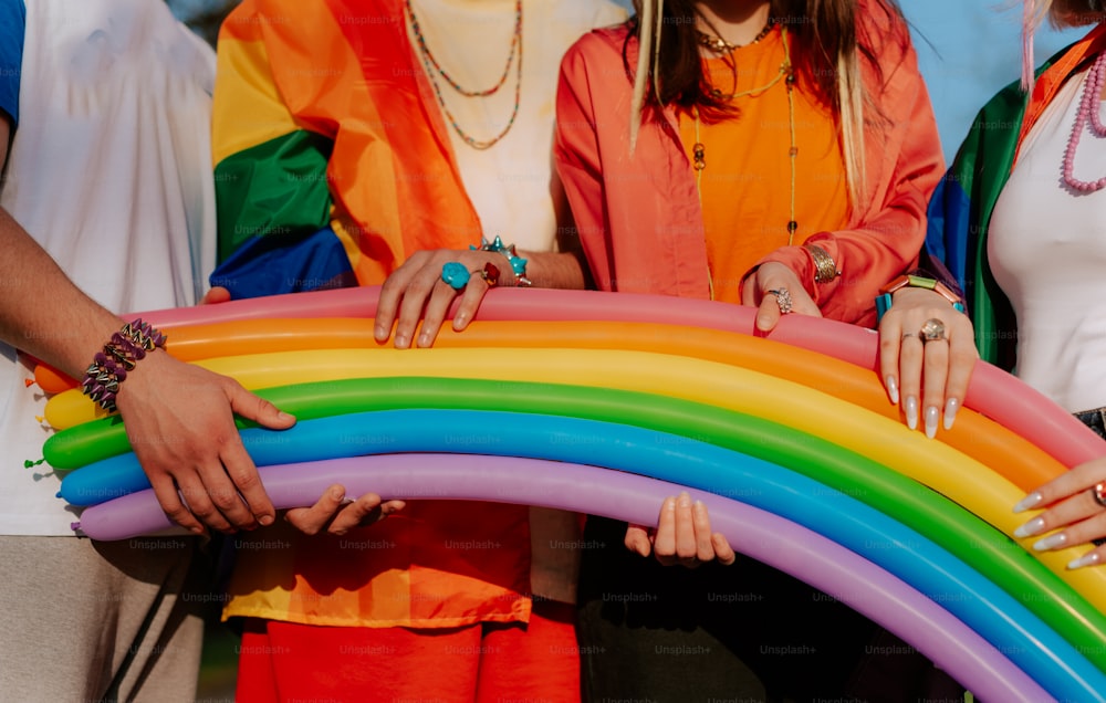 a group of people standing next to each other holding a rainbow shaped object