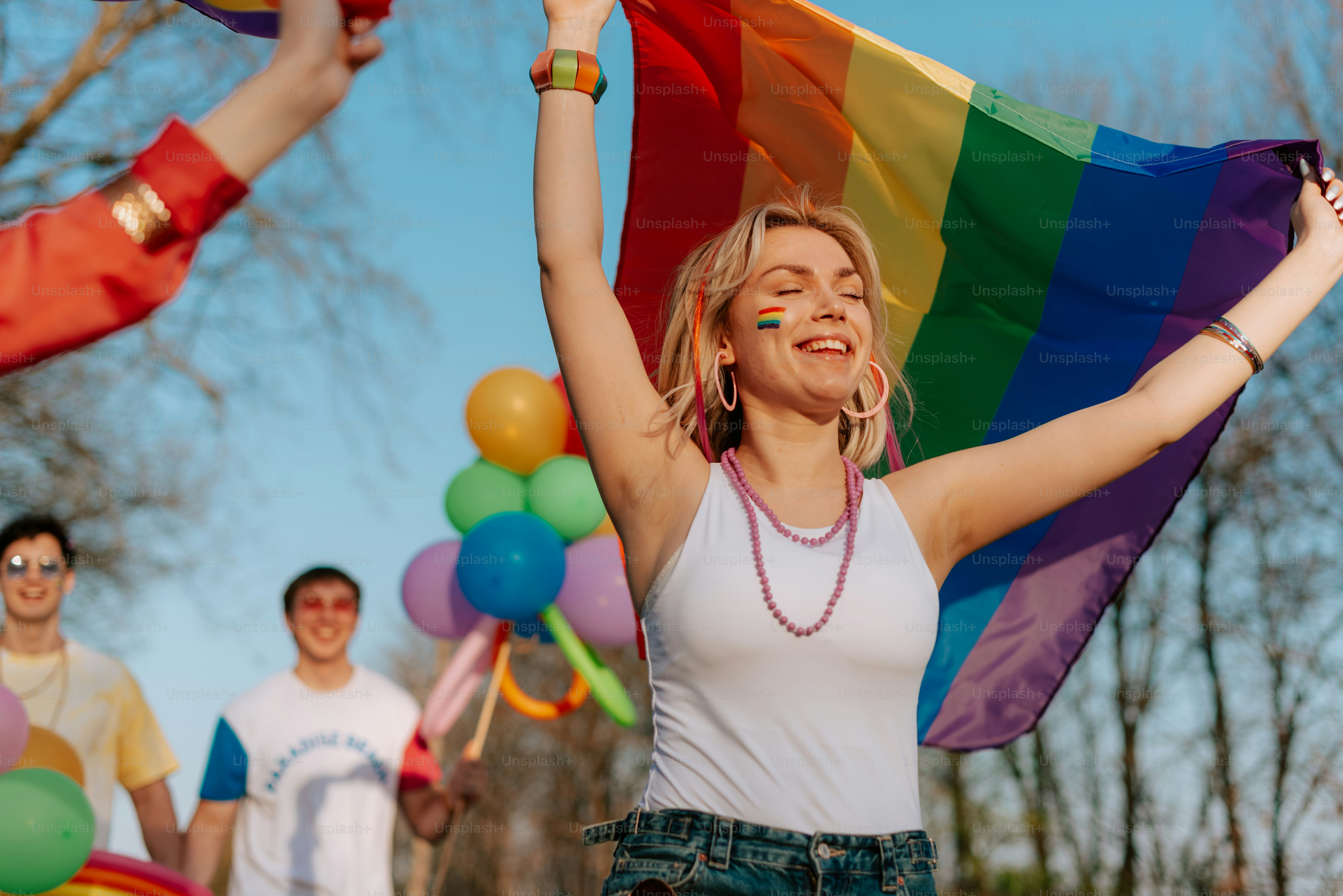 a woman holding a rainbow flag in front of a group of people