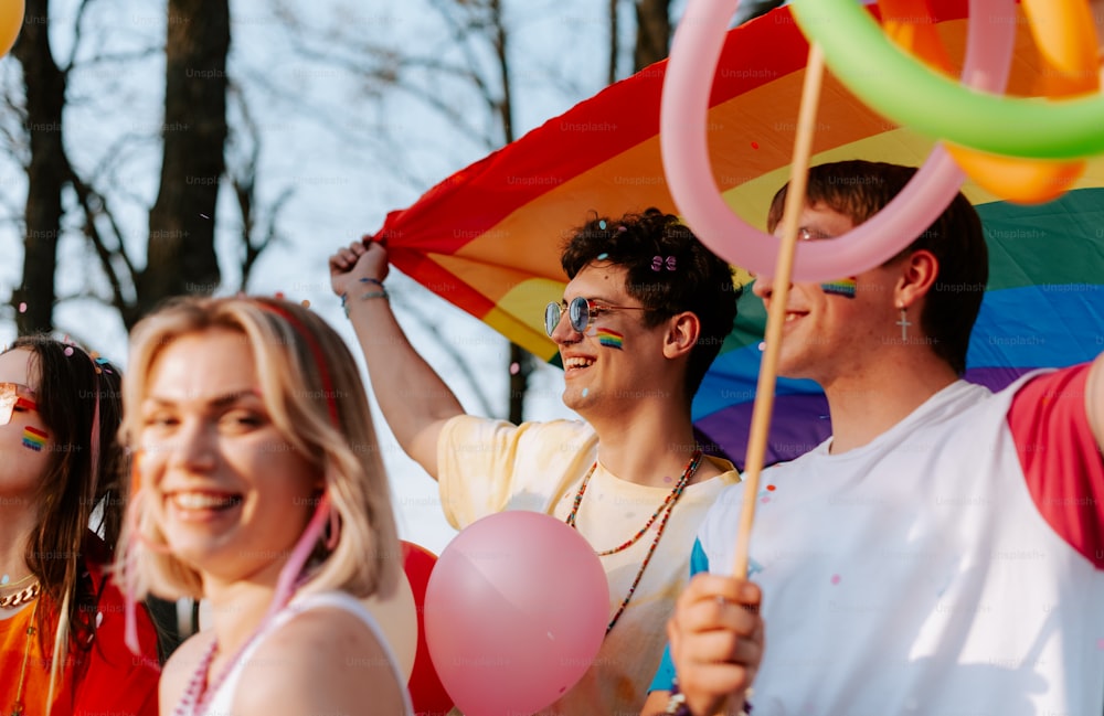 a group of people holding a rainbow flag and balloons