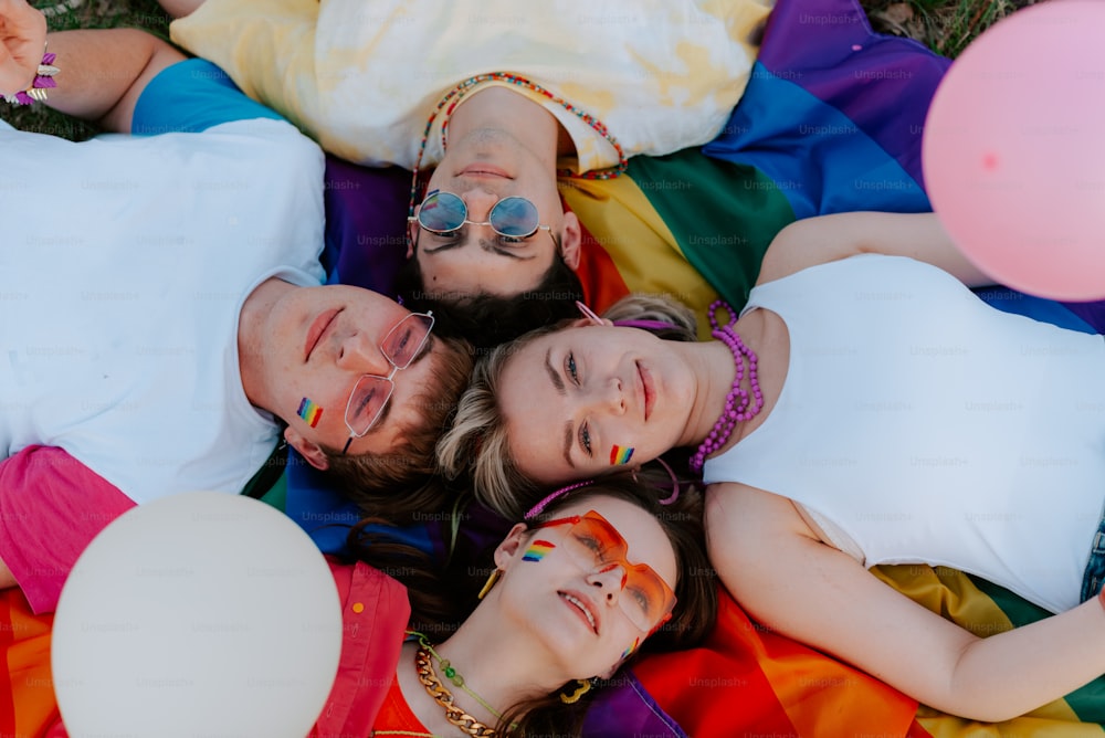 a group of people laying on top of a rainbow colored blanket