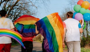 a group of people walking down a street holding a rainbow flag