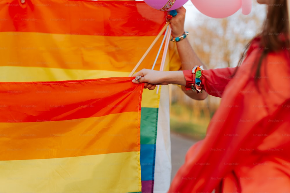 a woman holding a rainbow flag and balloons