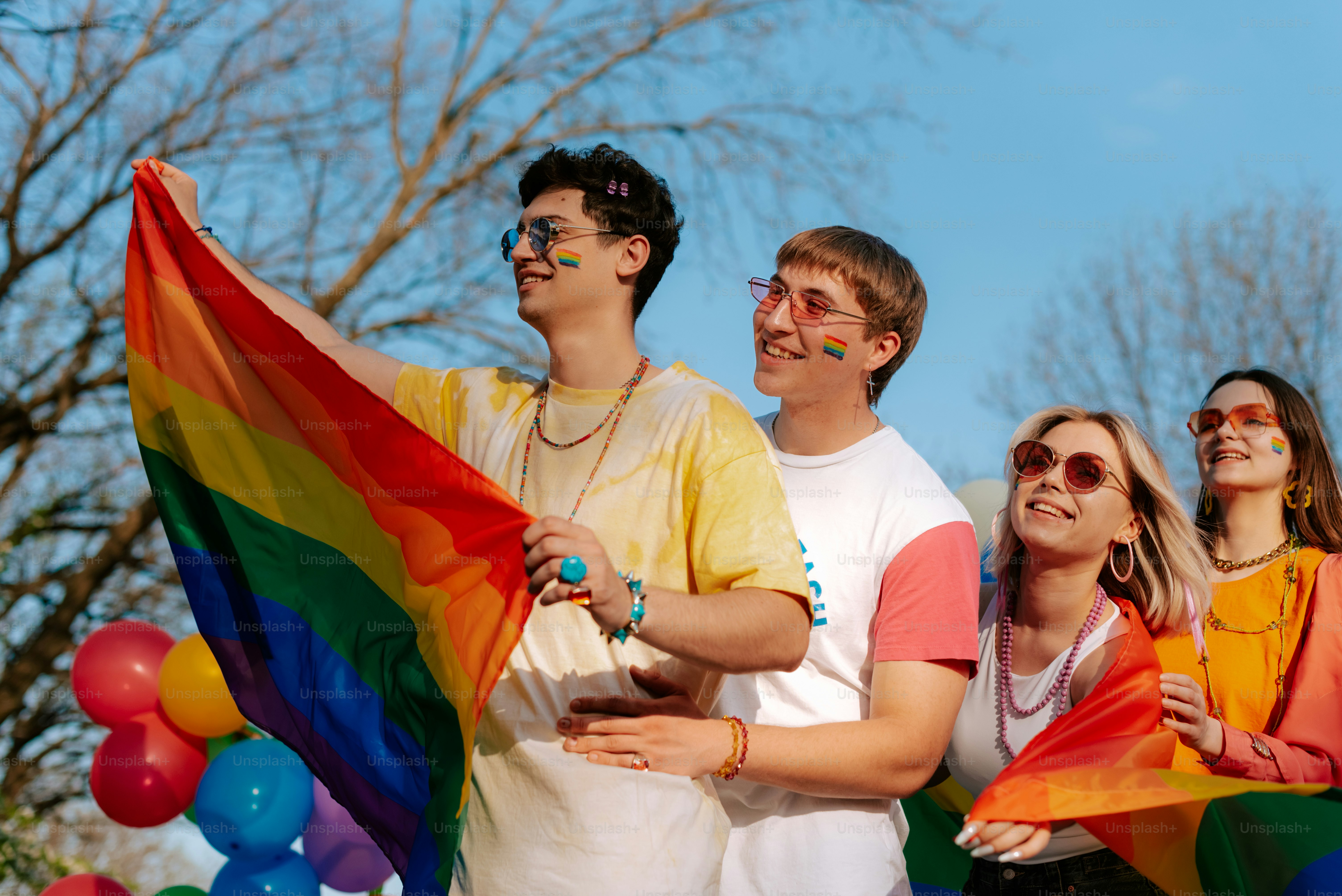 a group of people standing next to each other holding a rainbow flag