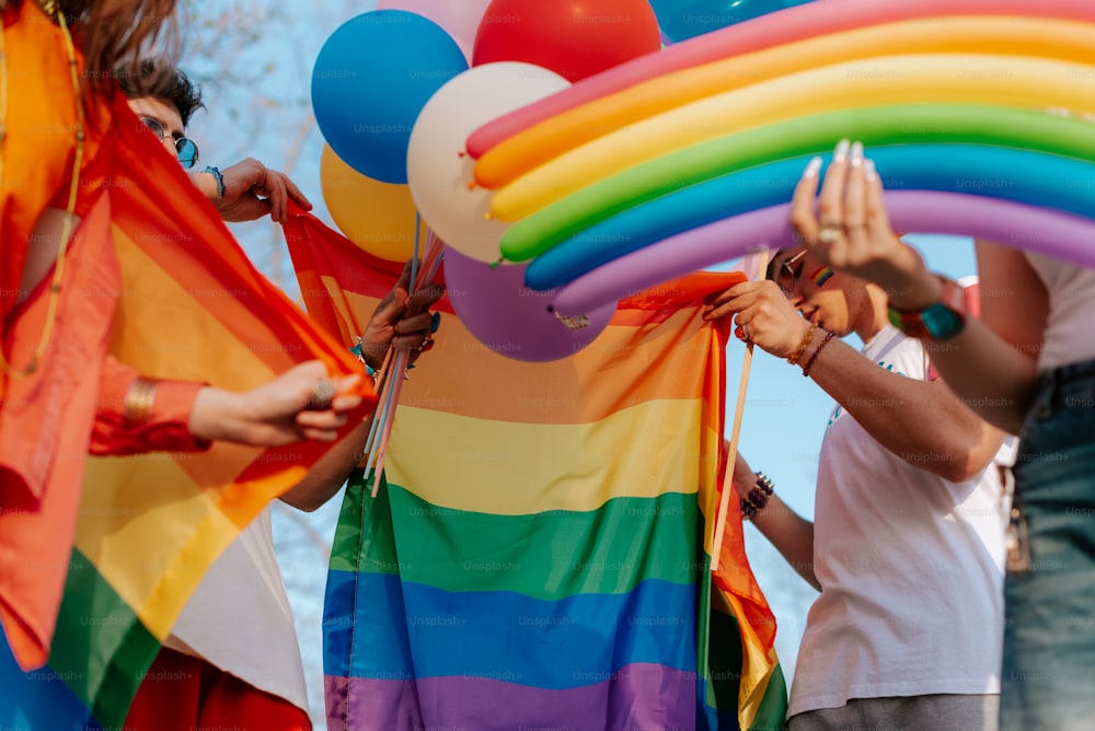 un gruppo di persone che tengono palloncini color arcobaleno