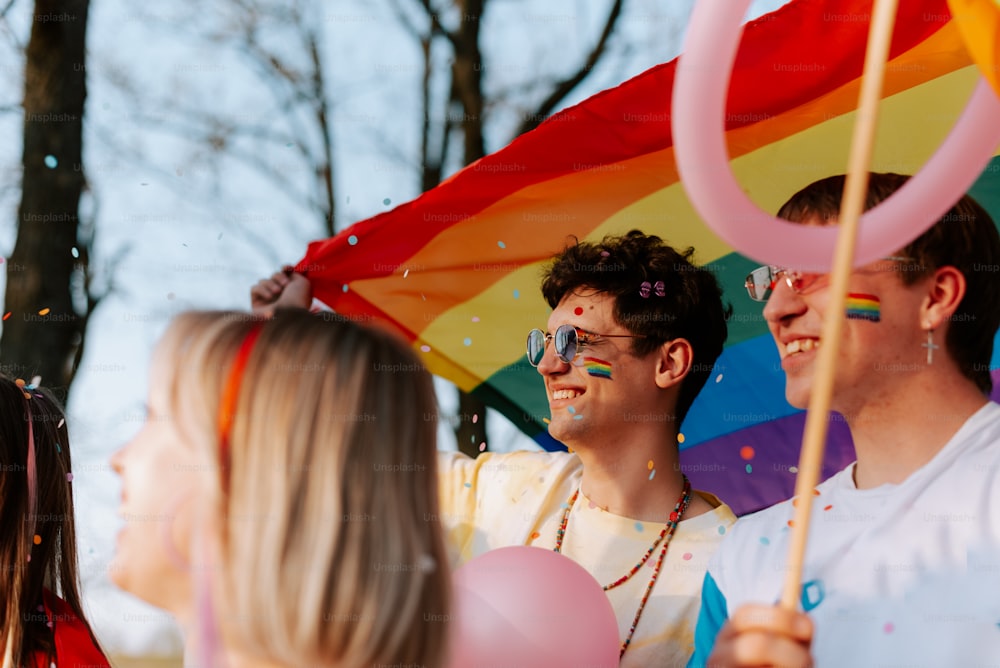 un gruppo di persone in piedi l'una accanto all'altra con in mano una bandiera arcobaleno