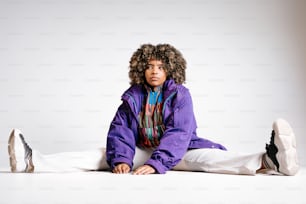 a young person sitting on the ground wearing a purple jacket