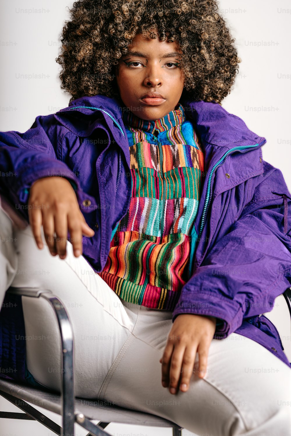 a woman sitting on a chair wearing a purple jacket