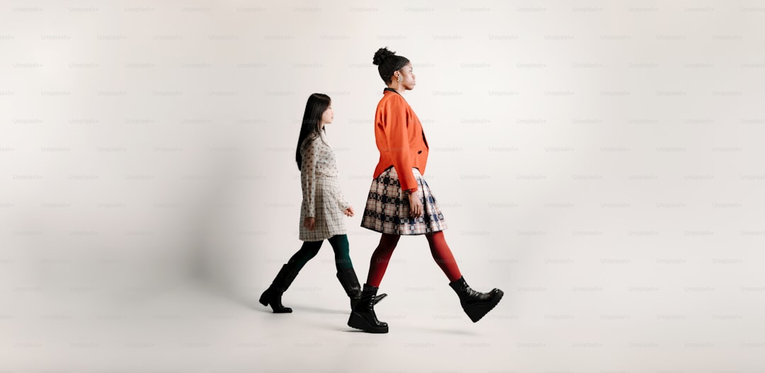 a couple of women walking across a white background