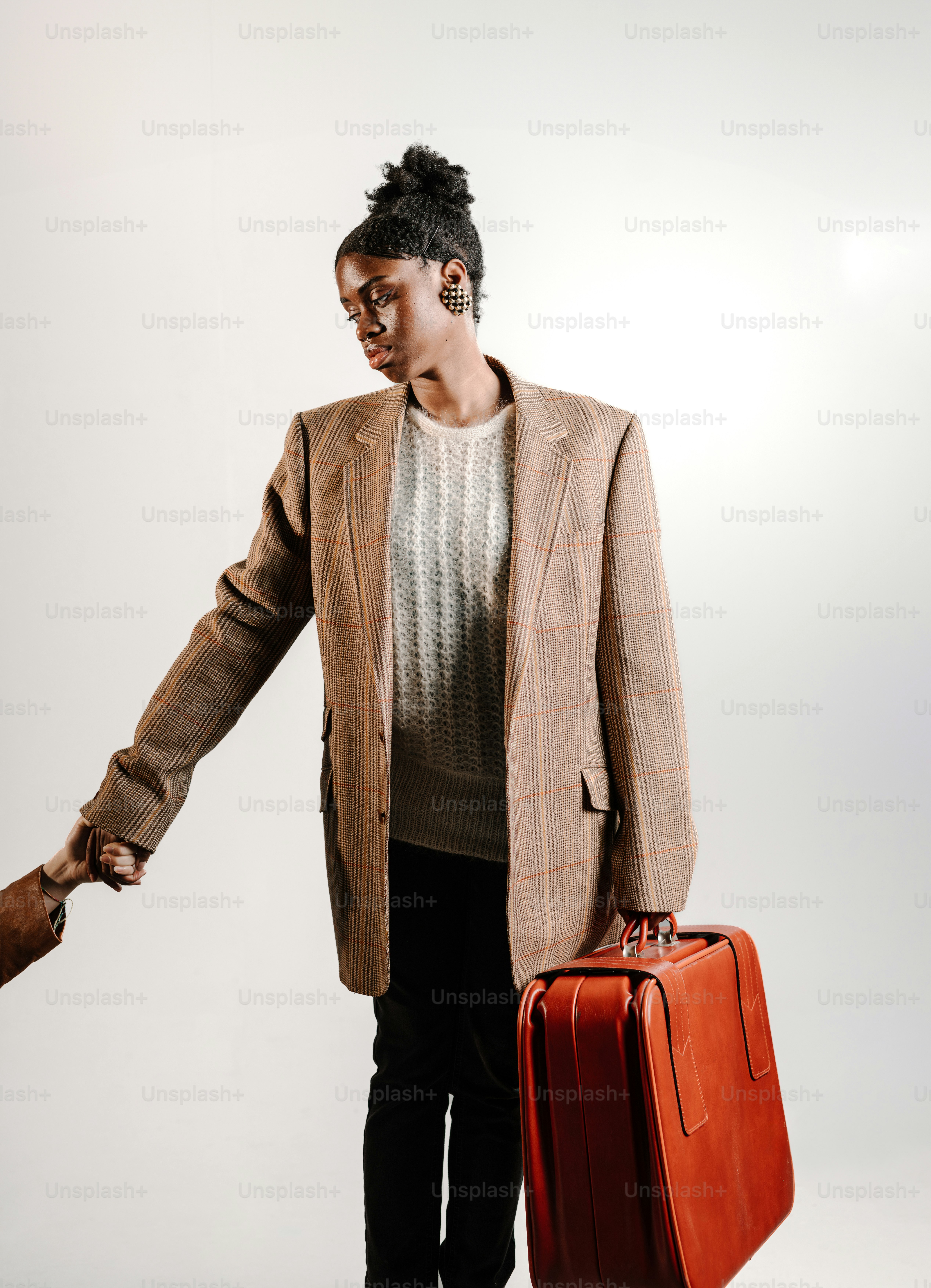 eine Frau im Anzug, die einen roten Koffer hält