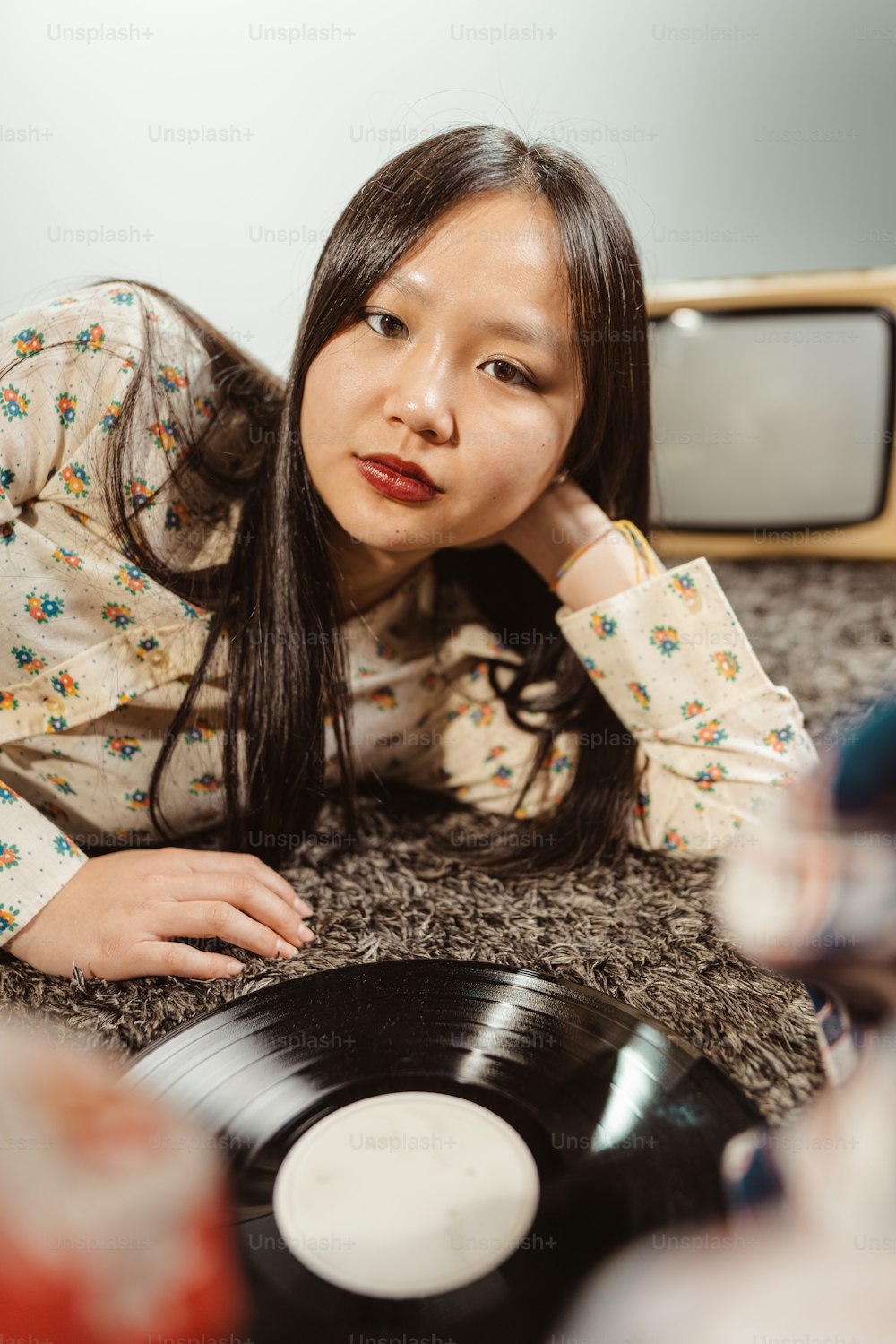 a woman laying on the floor next to a record