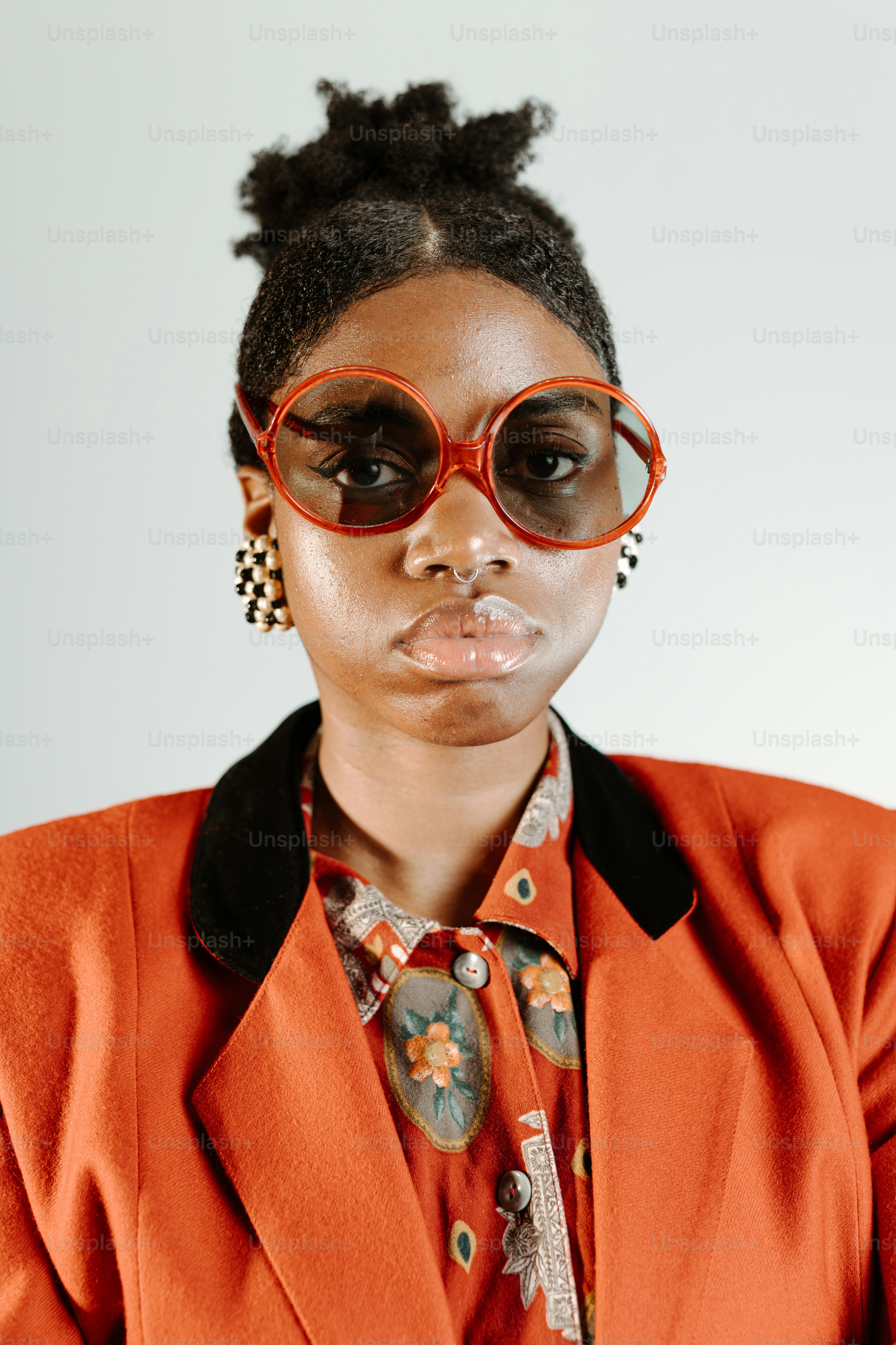 a woman in an orange jacket and red glasses