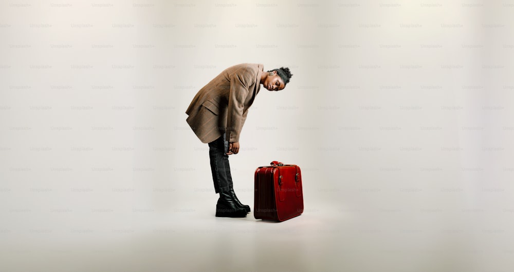 a man standing next to a red suitcase