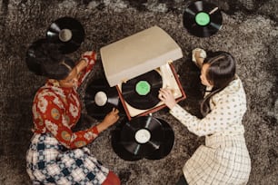 床に座ってレコードプレーヤーで遊んでいる二人の女性