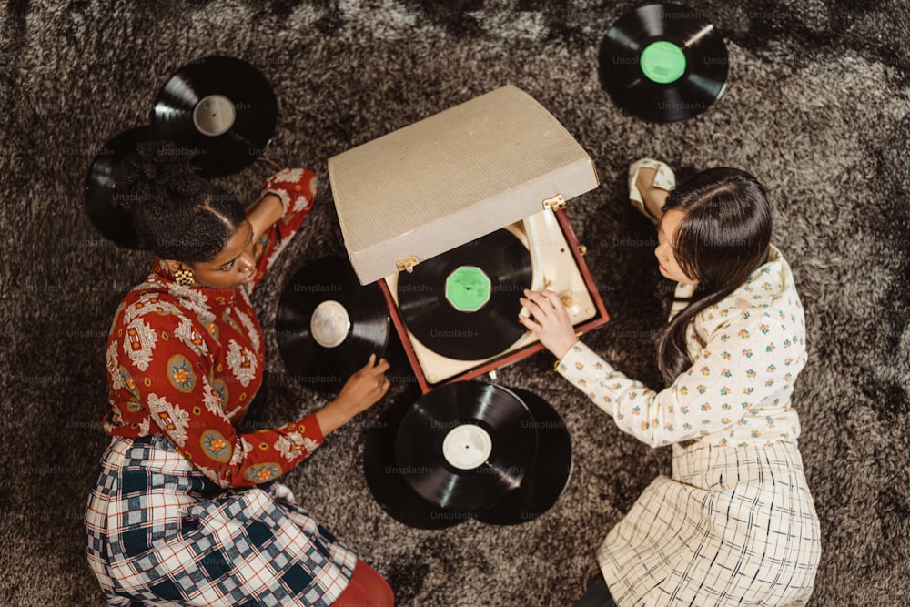 two women sitting on the floor playing with a record player