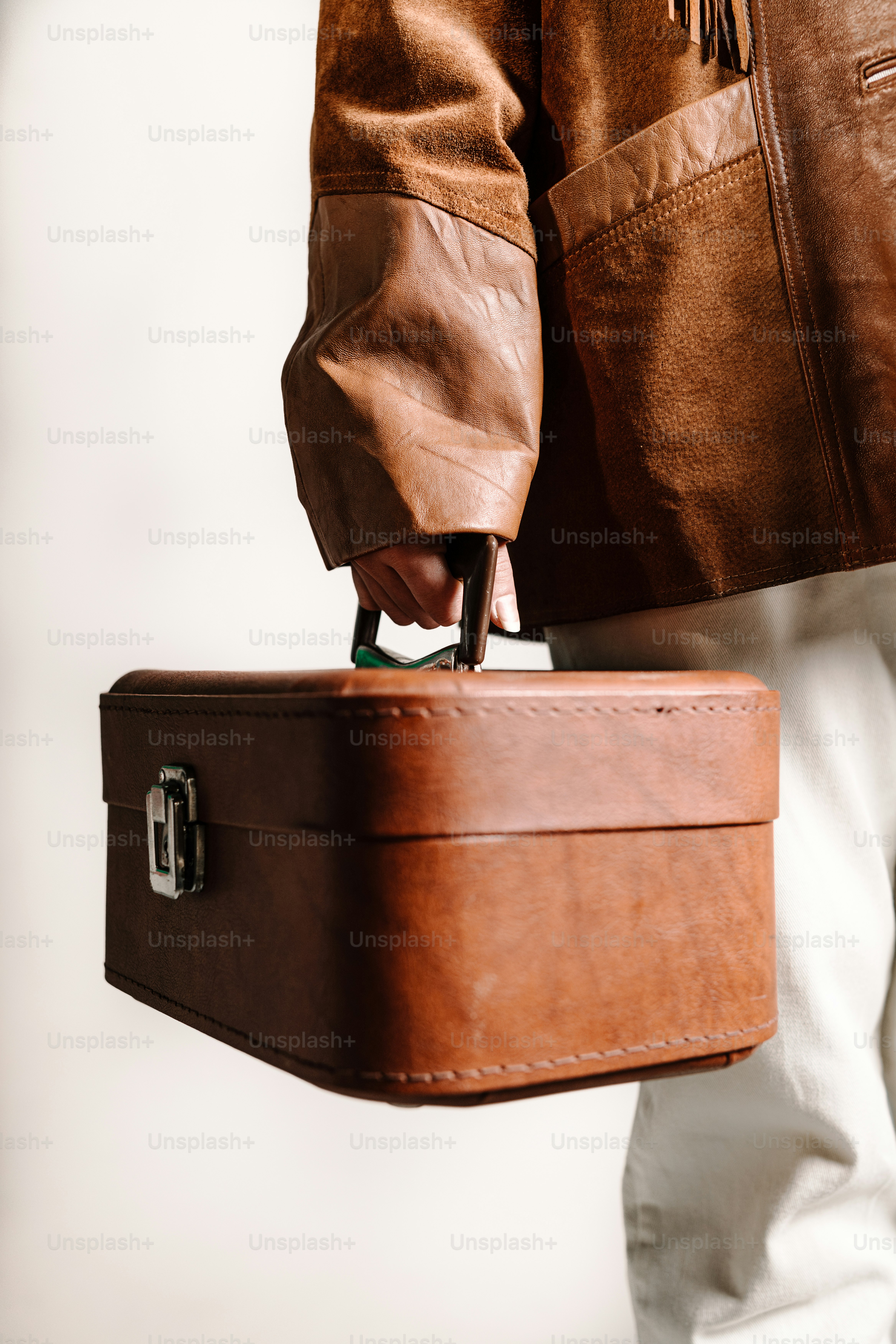 une personne tenant une valise brune à la main