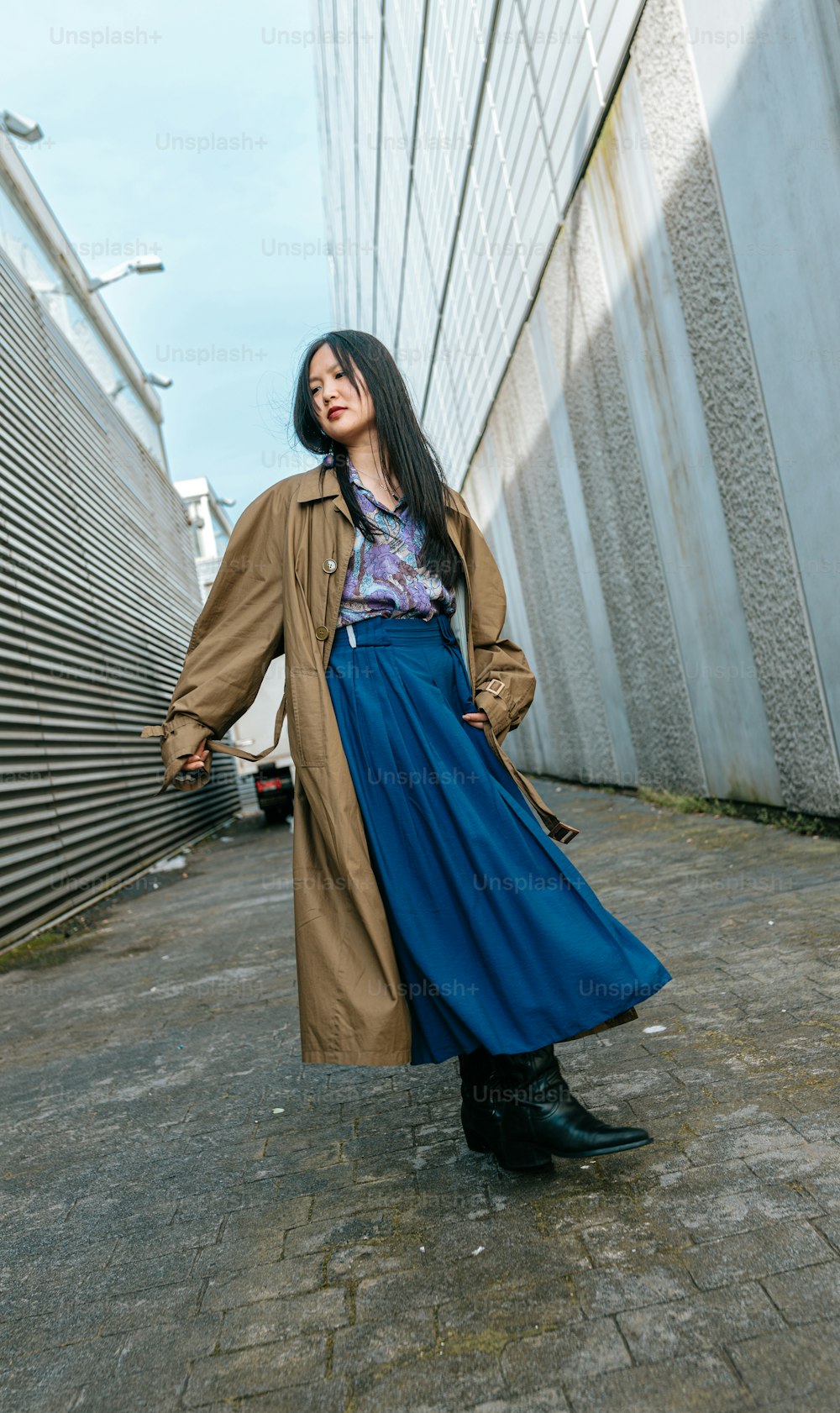 a woman in a long blue skirt and trench coat