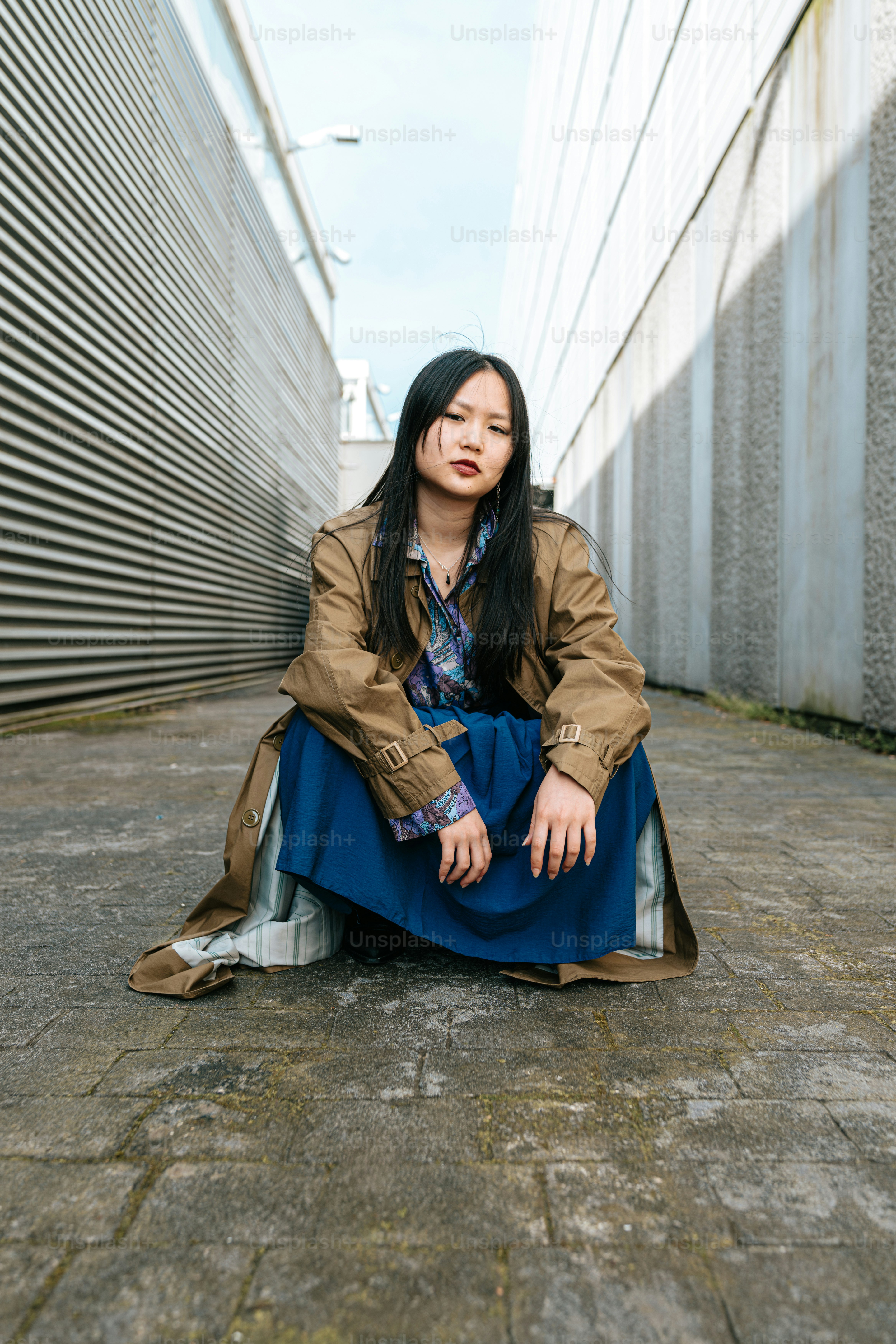 A woman sitting on the ground in front of a building photo – Office ...