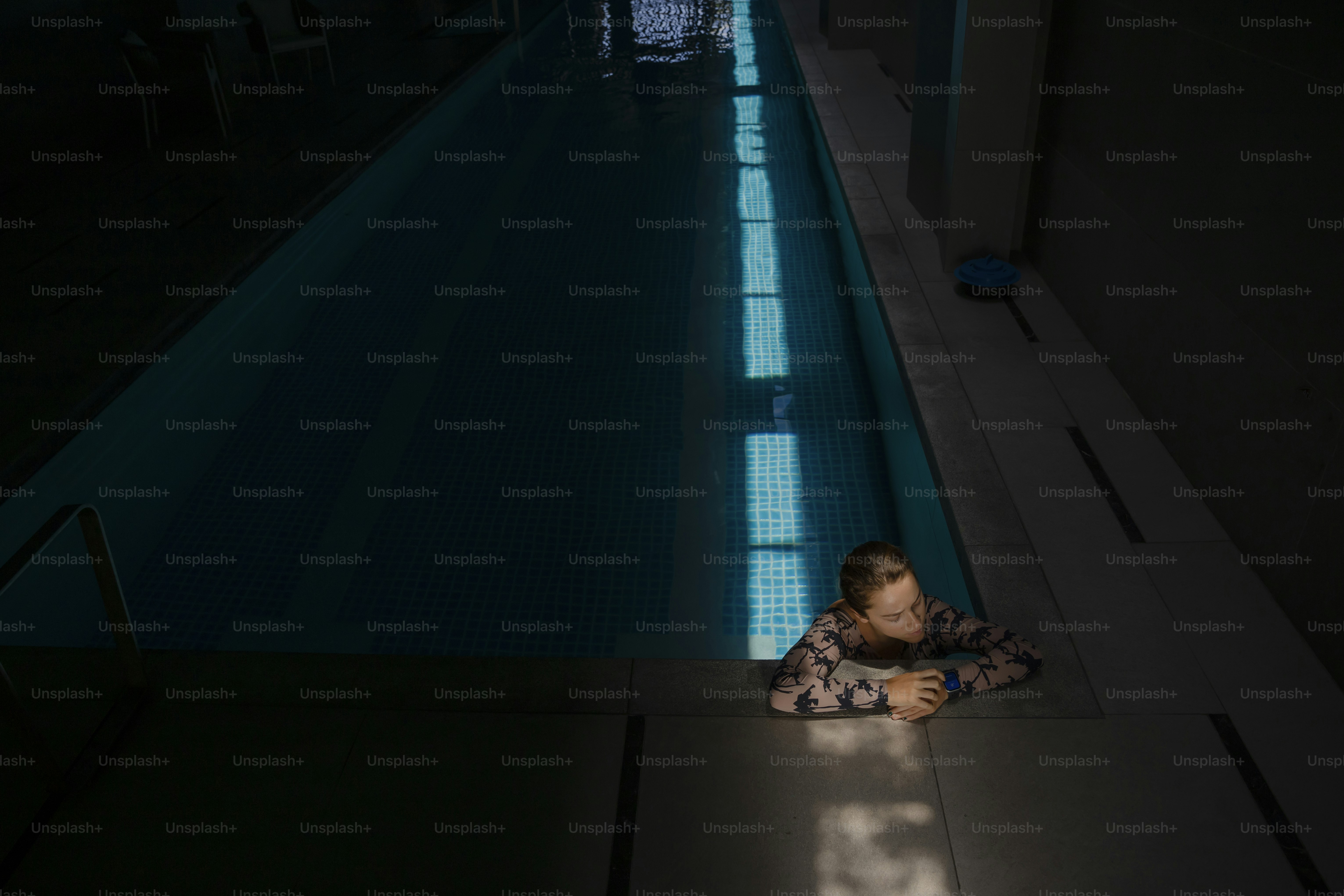 a little boy laying on the ground next to a swimming pool