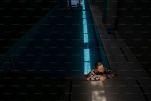 un petit garçon allongé sur le sol à côté d’une piscine