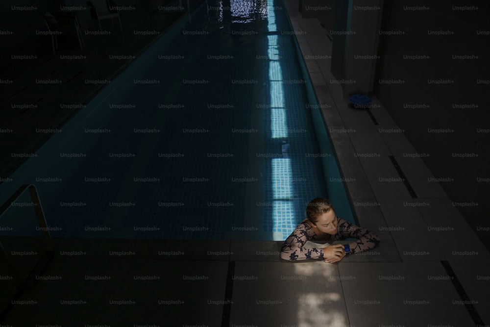 a little boy laying on the ground next to a swimming pool