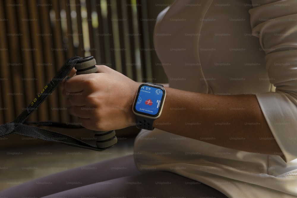 a woman is holding a smart watch with a blue screen