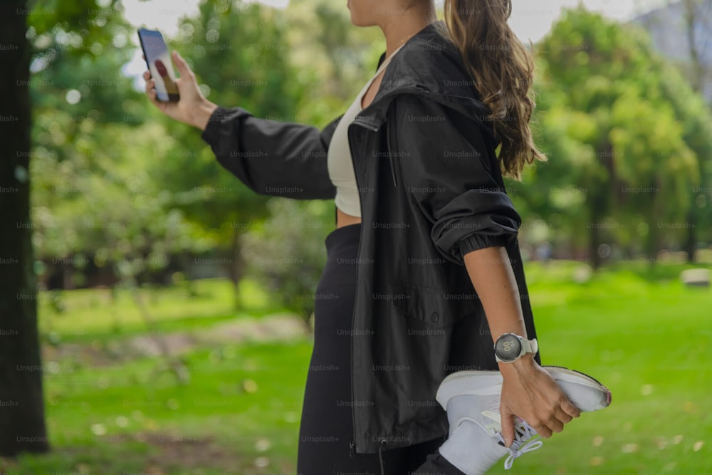 Una mujer sosteniendo un teléfono celular en un parque