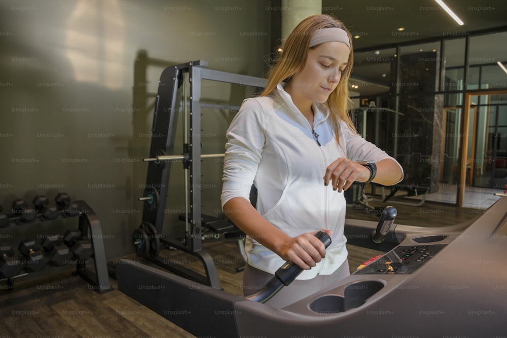 한 여성이 체육관에서 기계를 다루고 있다