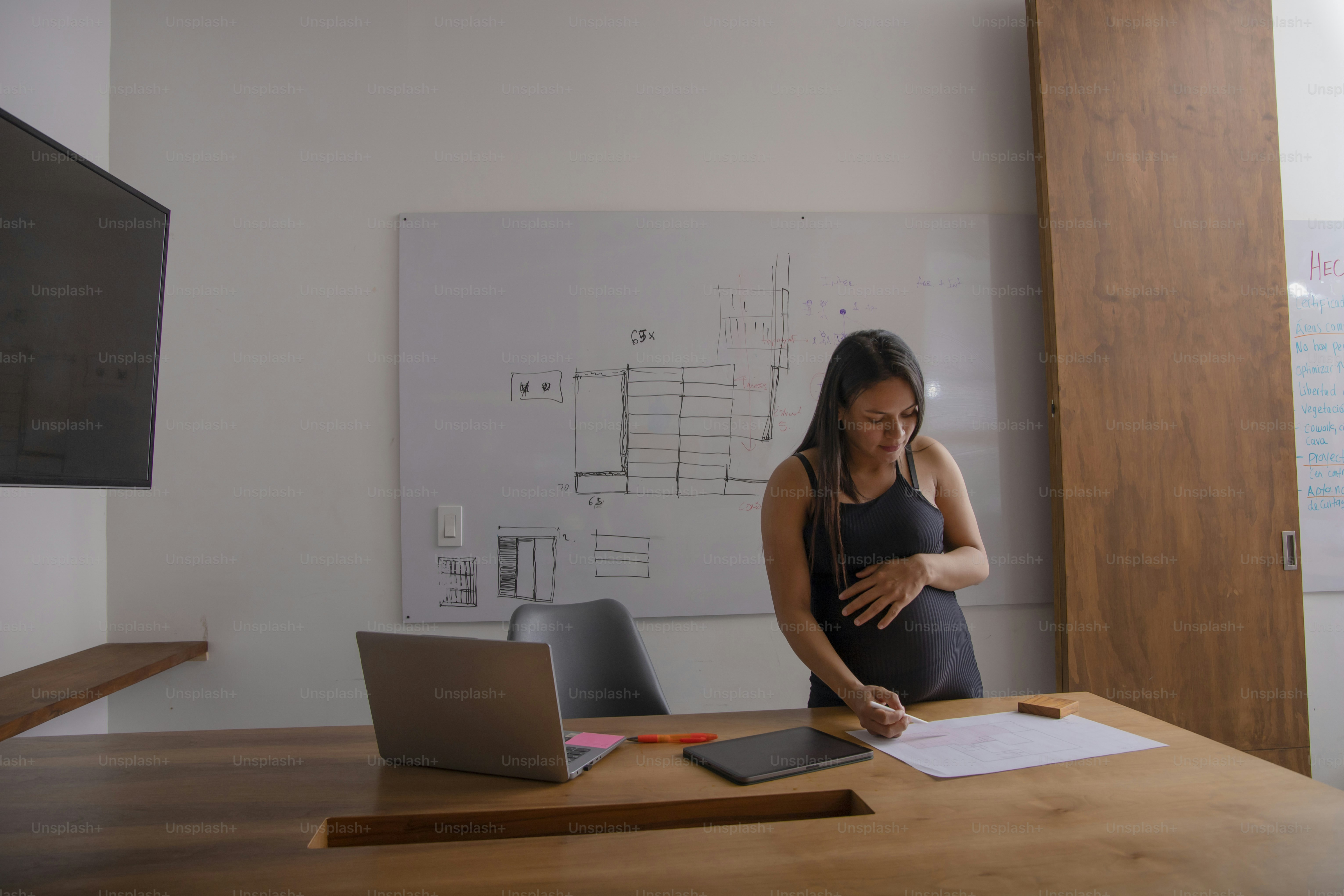 A pregnant woman standing in front of a laptop computer photo – Office ...