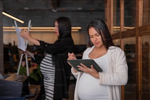 a pregnant woman looking at a tablet computer