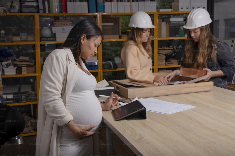 a pregnant woman standing in front of a desk