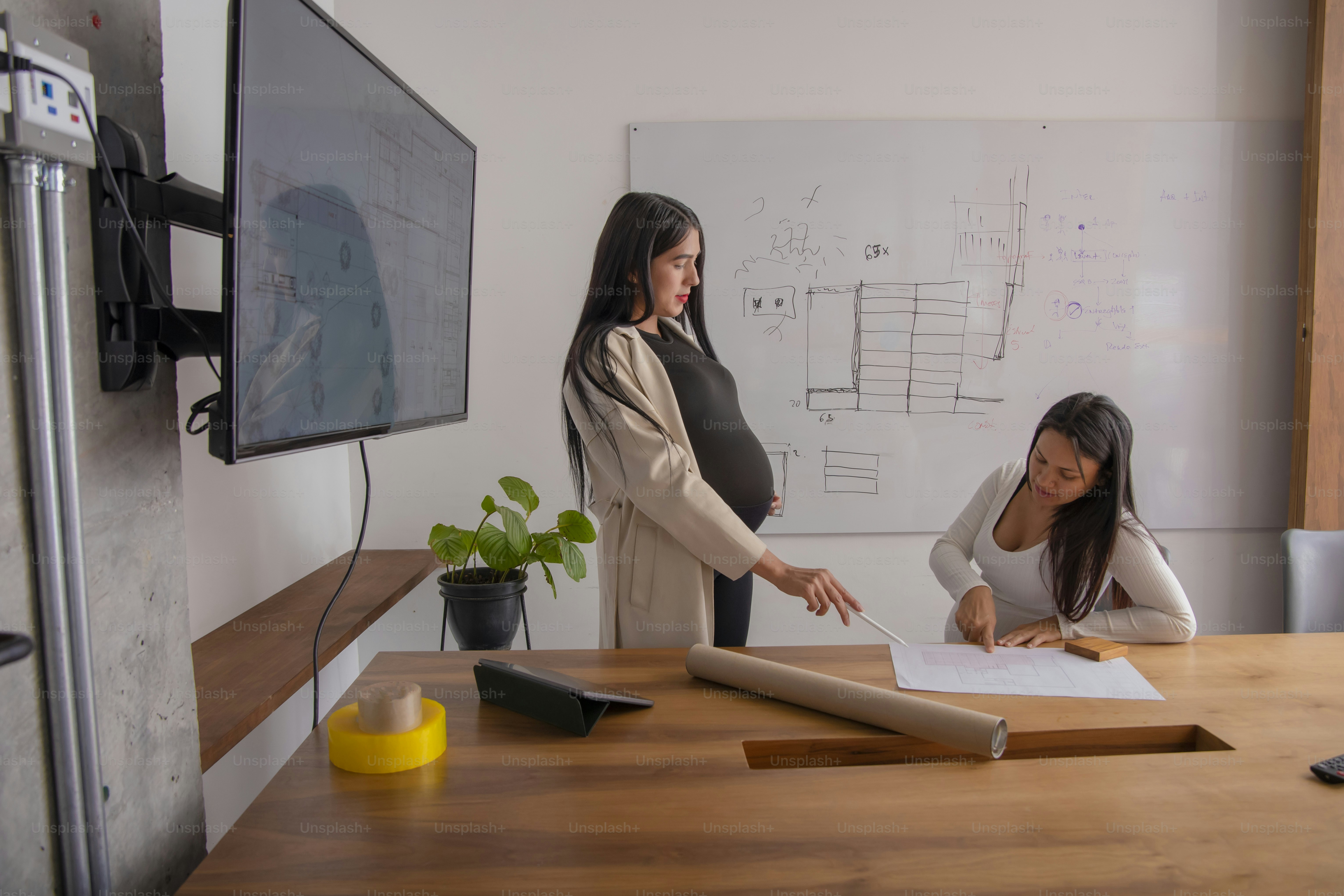a woman pointing at a piece of paper on a table