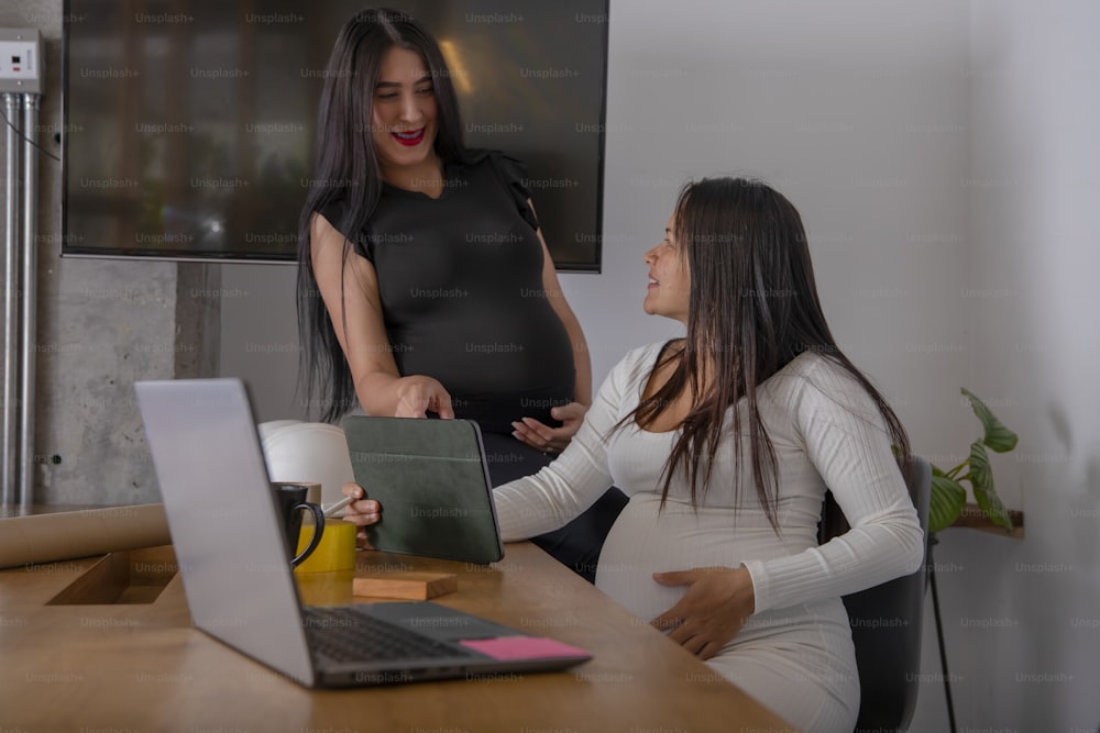 a pregnant woman standing in front of a laptop computer