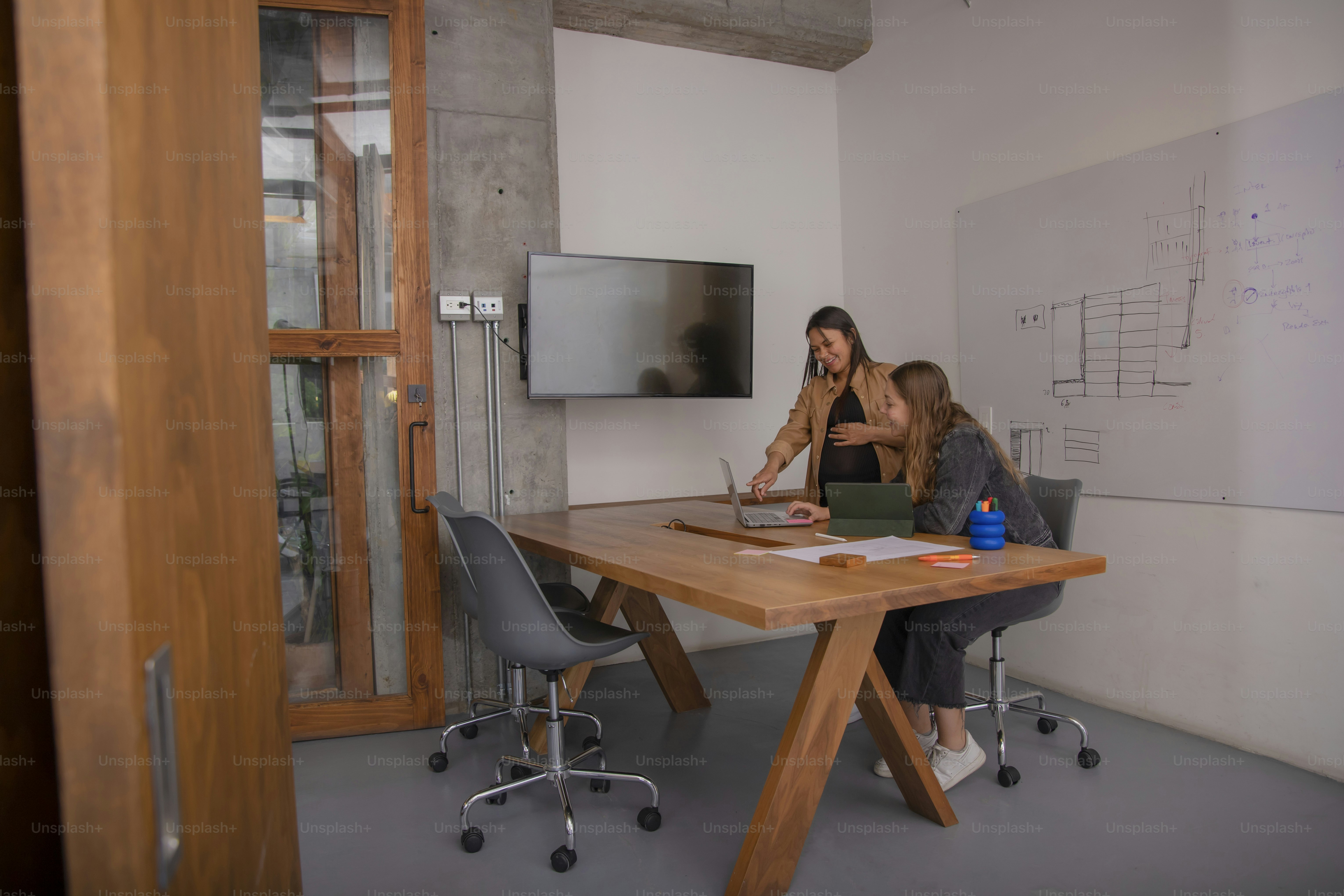 two women sitting at a table with a laptop