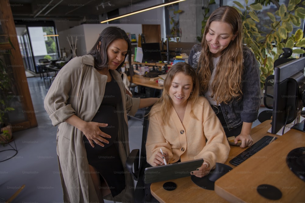 a group of women standing around a computer desk