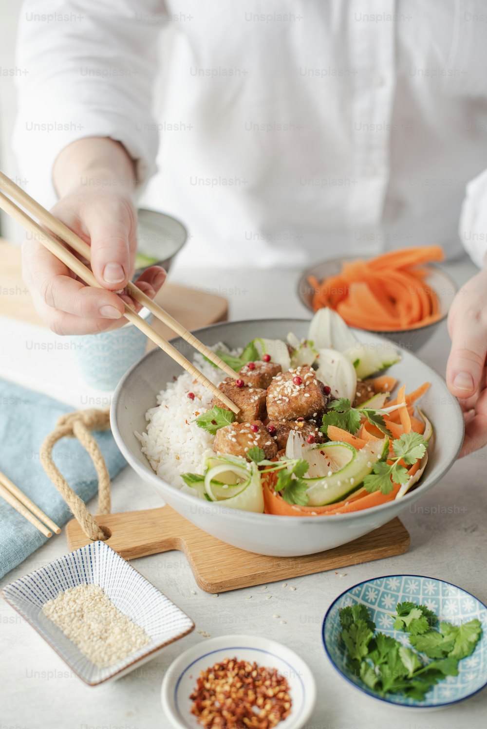 a person holding chopsticks over a bowl of food