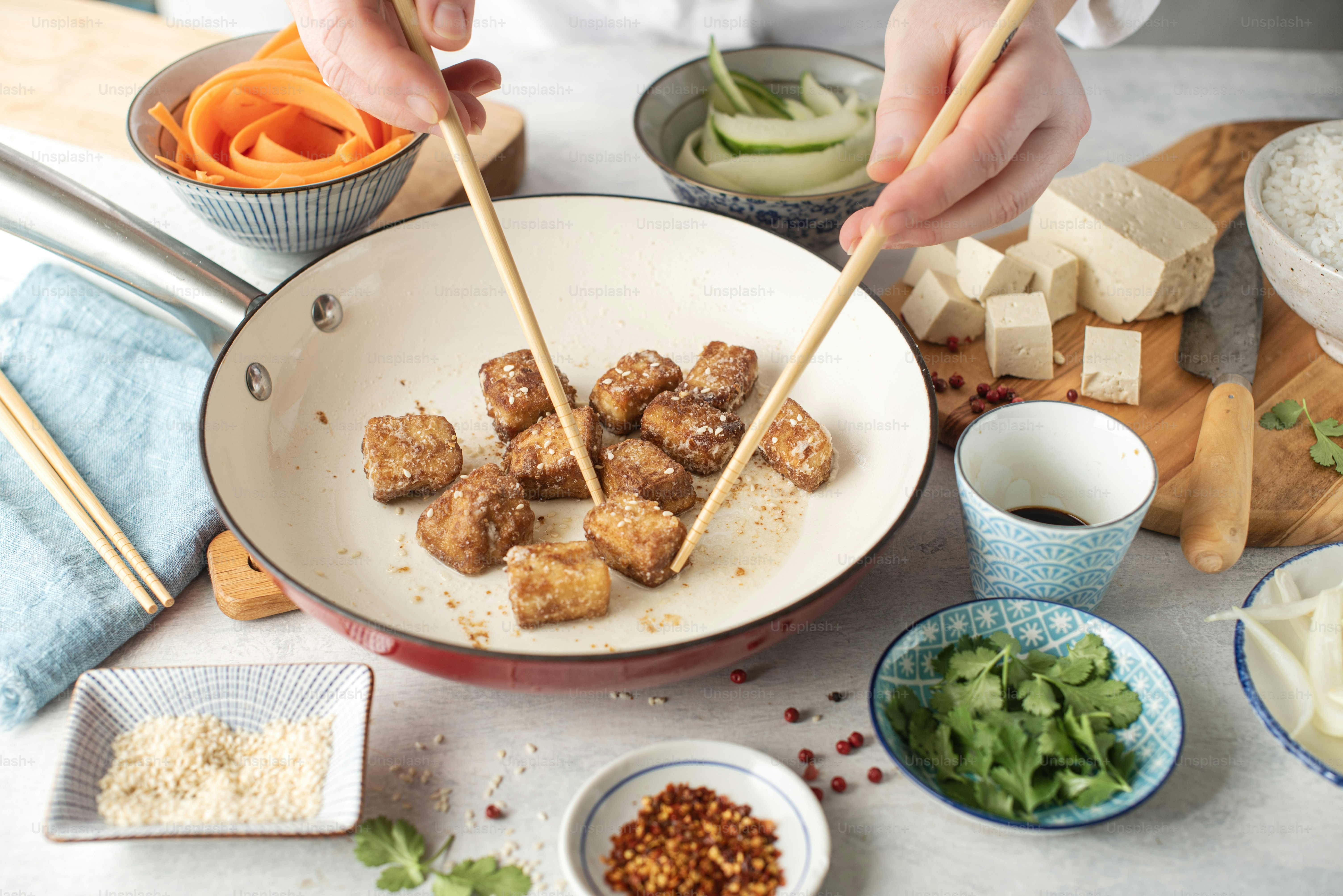 a person holding chopsticks over a bowl of food