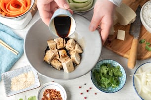 a person pouring sauce into a bowl of food