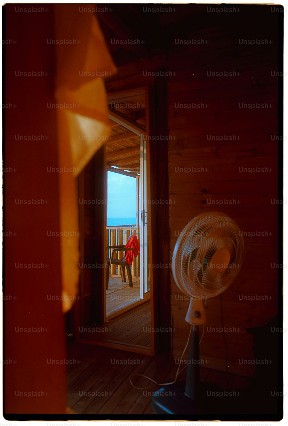 Un ventilador sentado encima de un suelo de madera junto a una ventana