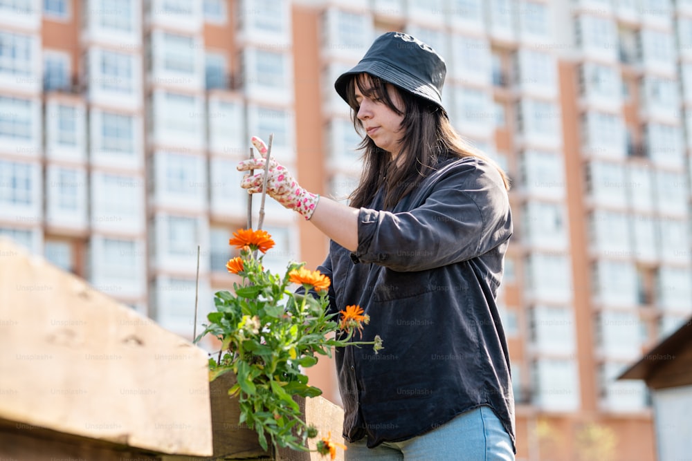 a woman standing next to a flower pot