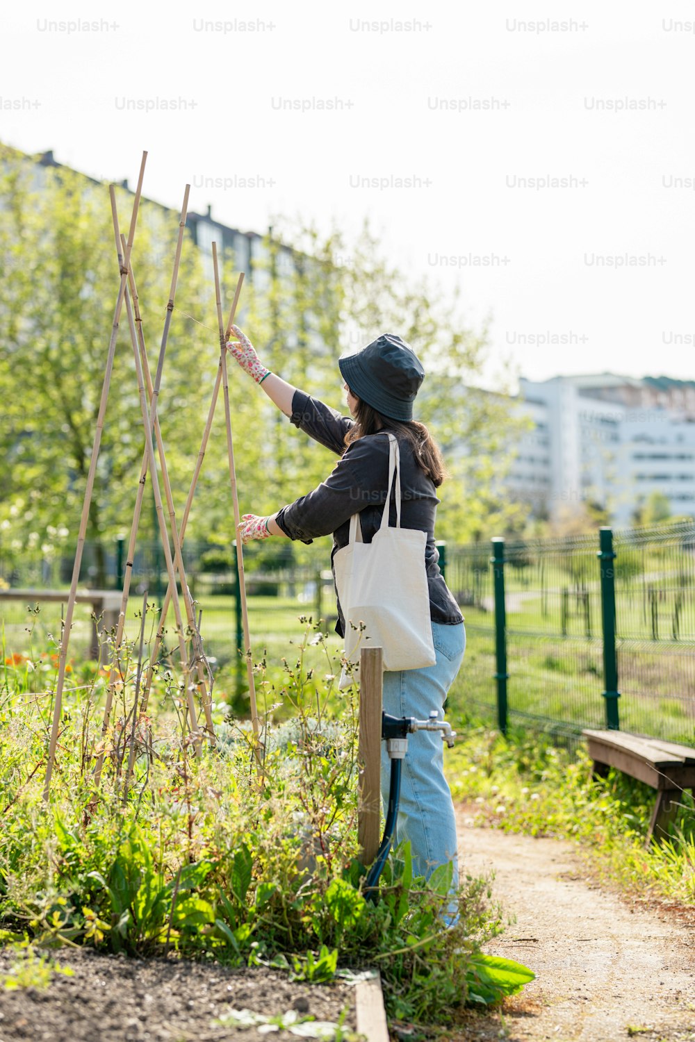 a woman standing in a garden with a bag on her shoulder