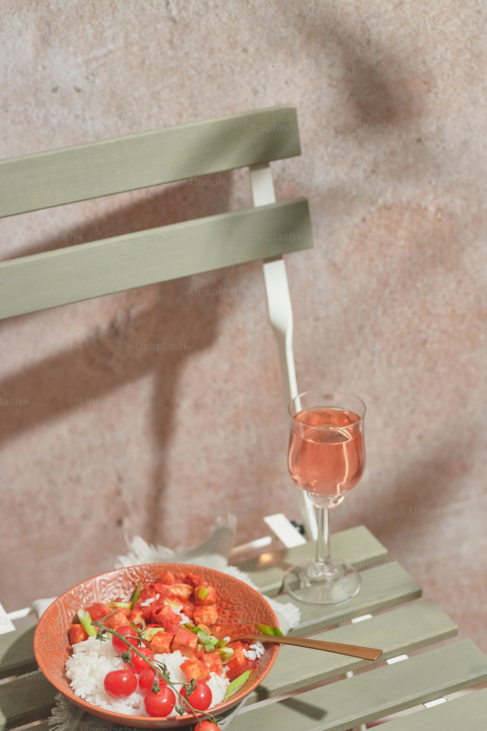 a bowl of food sitting on a table next to a glass of wine