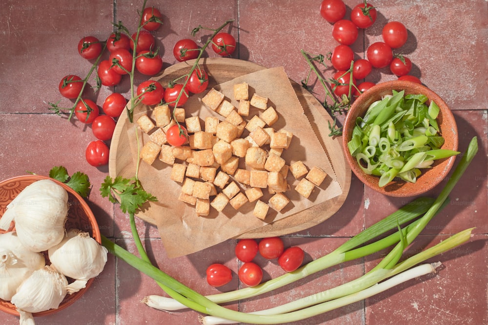 a wooden cutting board topped with tofu and vegetables