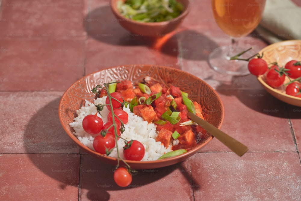 eine Schüssel mit Reis, Tomaten und Salat auf einem Tisch